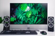 turned-on flat screen computer monitor with speakers and keyboard