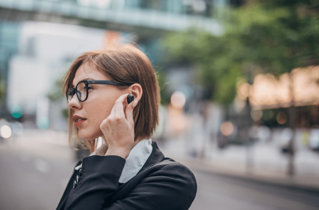 Lady in Business Suite puts an Earbud into her ear - easy to put and fitting perfectly